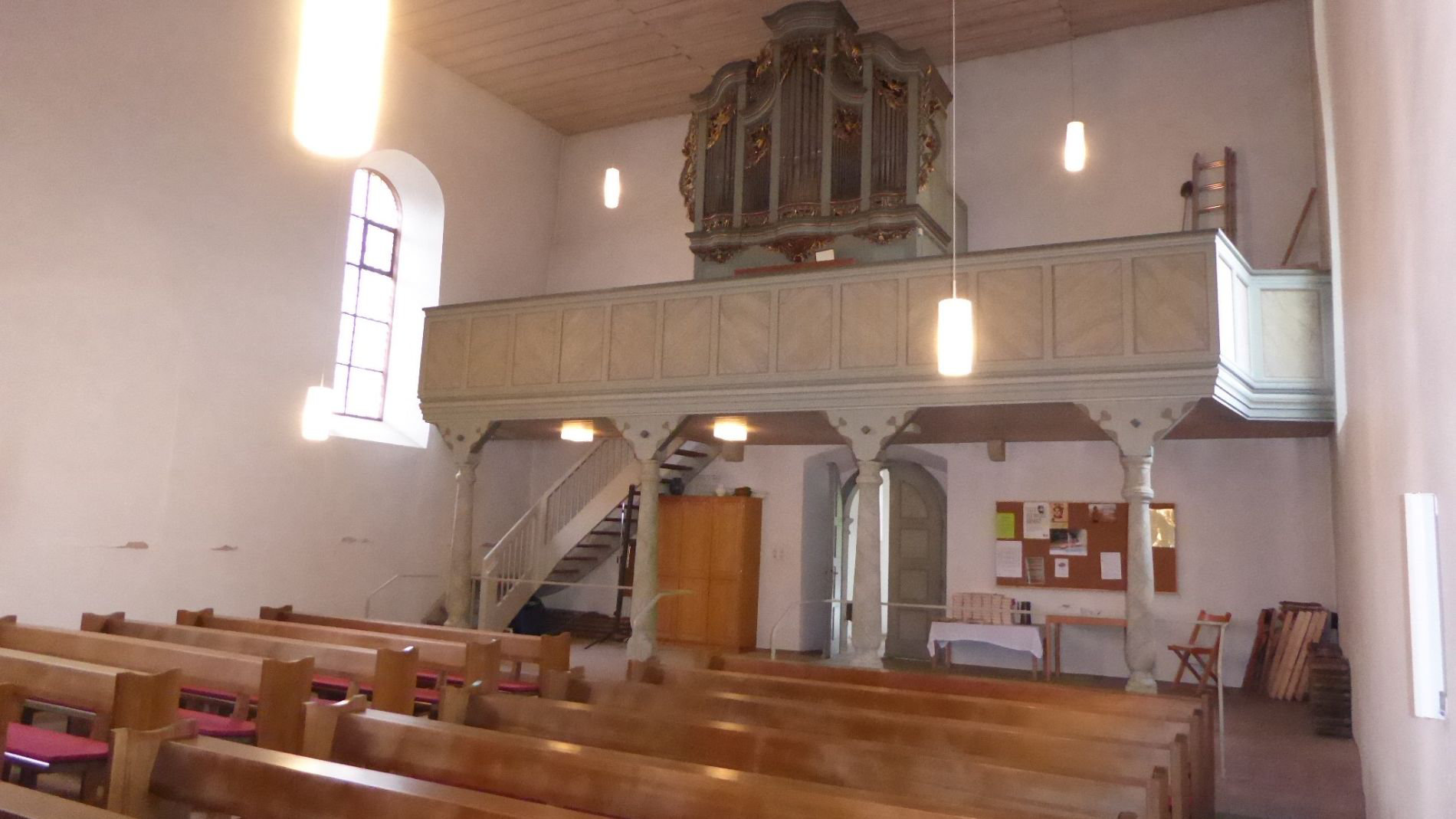 Historischer Kirchenraum vor der Sanierung mit Orgel, Empore und traditionellen Holzbänken.