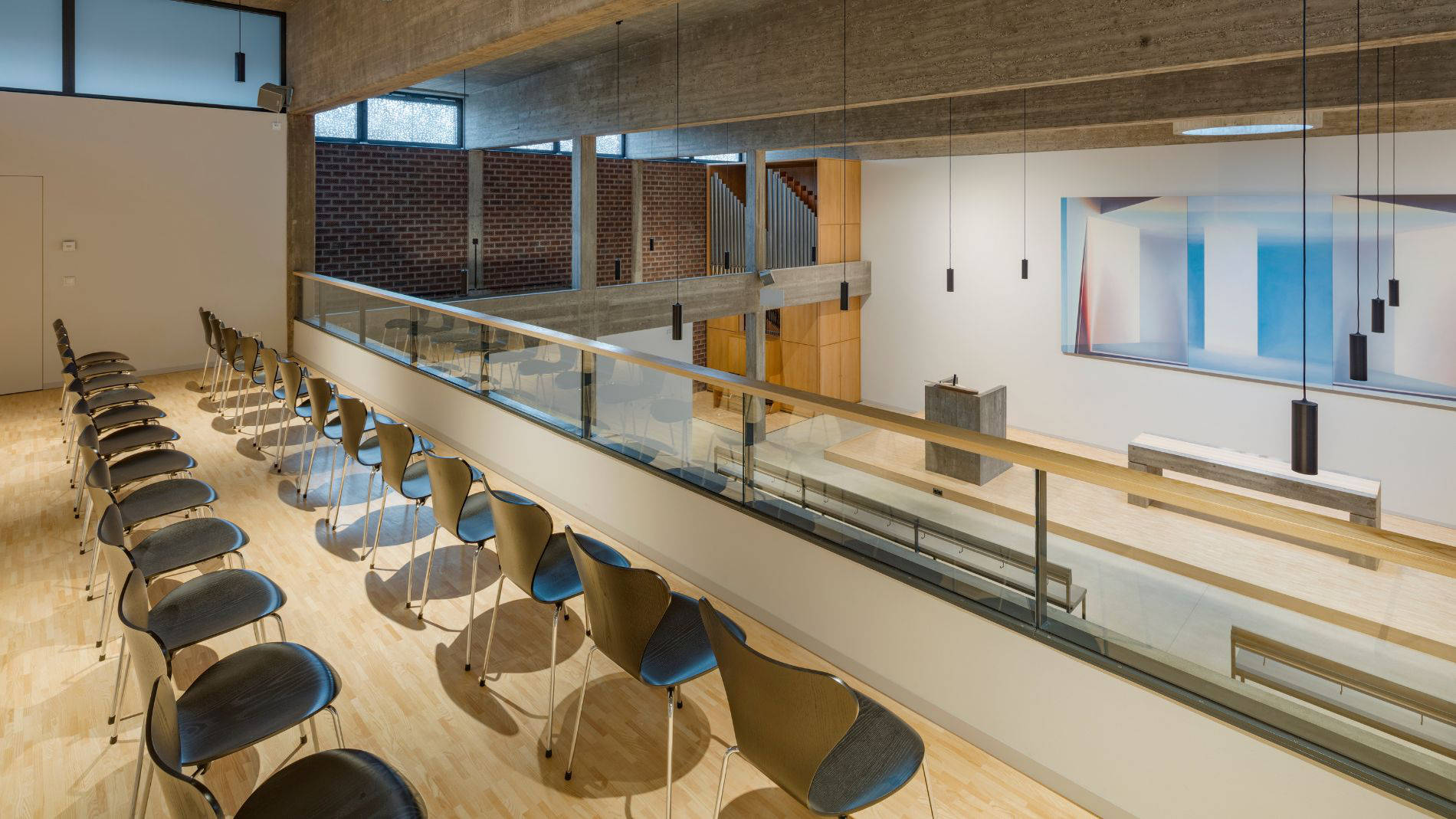 Empore und Obergeschoss der sanierten Kirche Haßloch Nord mit modernen Sitzreihen, Glasbrüstung und Blick auf den Altarraum.