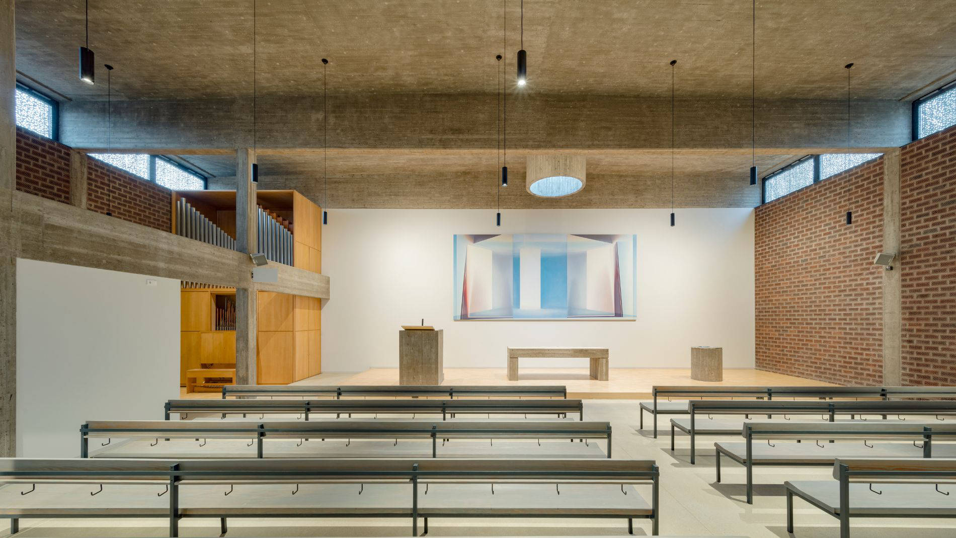 Sanierter Kirchenraum der Kirche Haßloch Nord mit minimalistischer Altarwand, moderner Beleuchtung und Betonmöbeln.