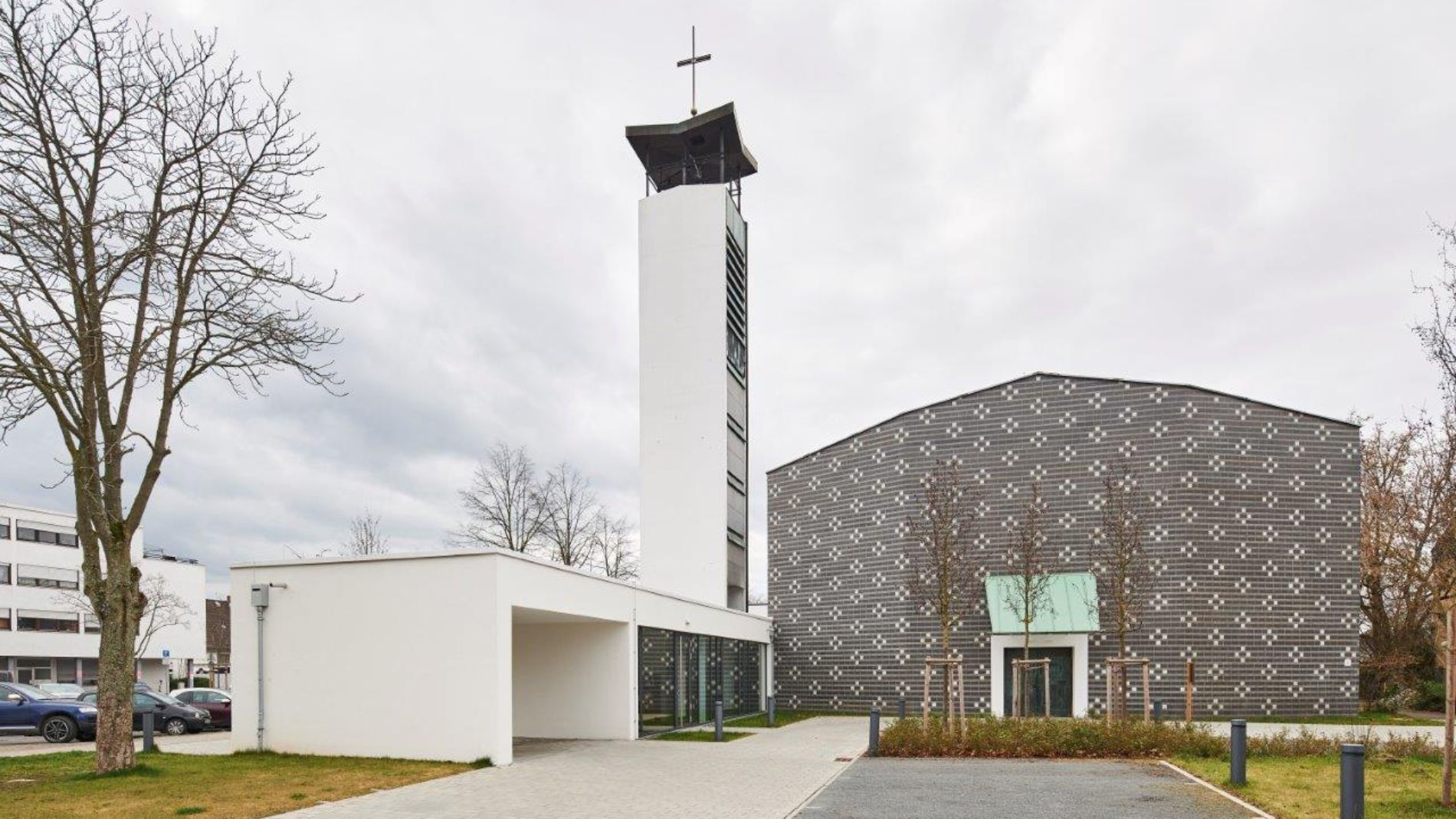 Moderne Außenansicht der Kirche Rüsselsheim nach dem Umbau mit markanter Ziegelfassade und weißem Glockenturm.