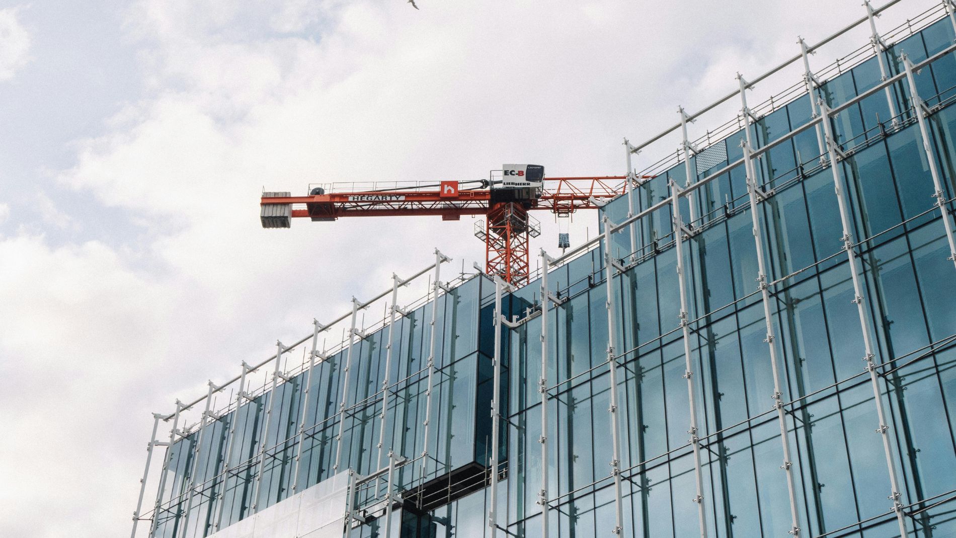 Glass-fronted building under construction with crane