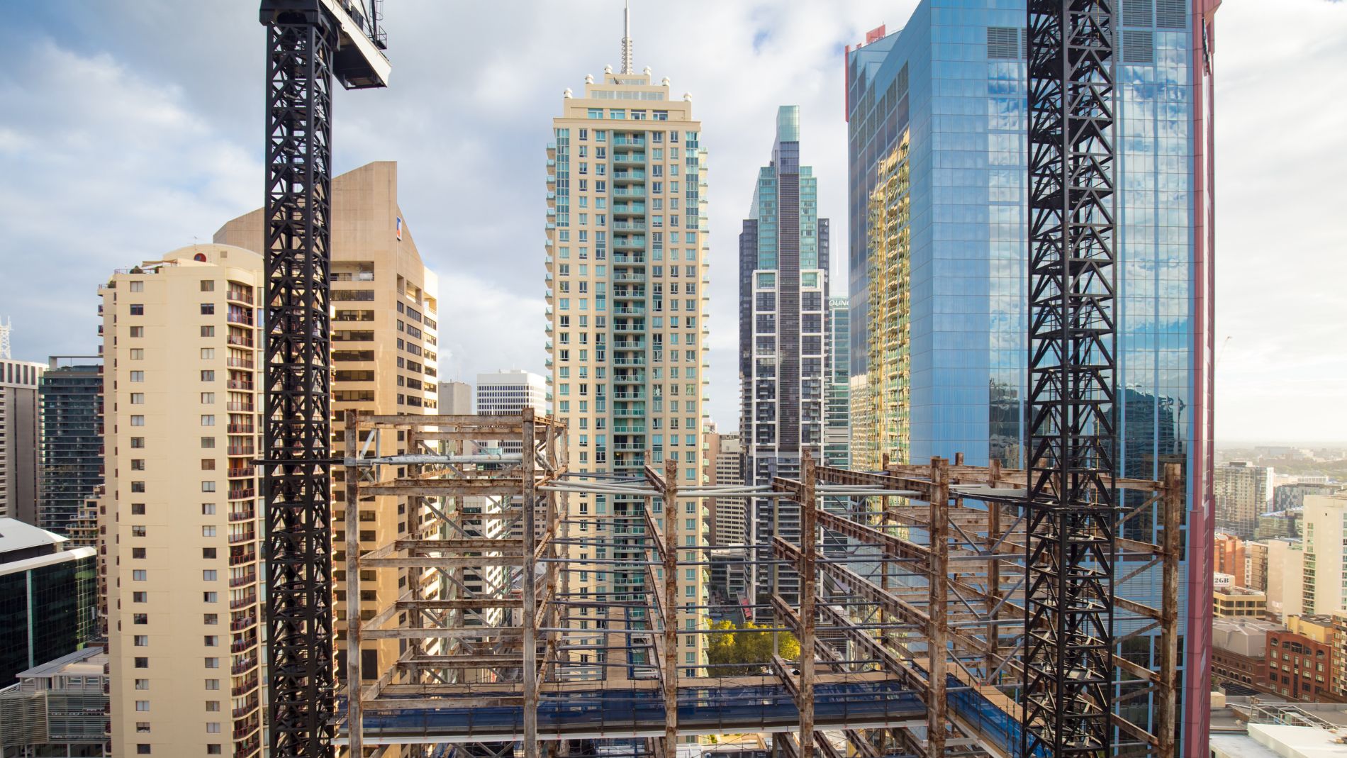 Construction site with steel framework of a high-rise building in front of a modern skyline – symbol of construction industry and urban growth.