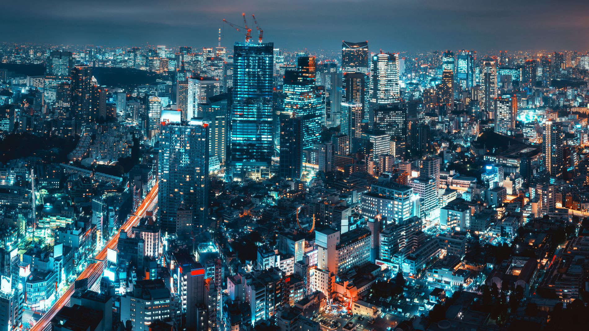 Night-time cityscape with illuminated skyscrapers and street lights, representing urban development and modern infrastructure.