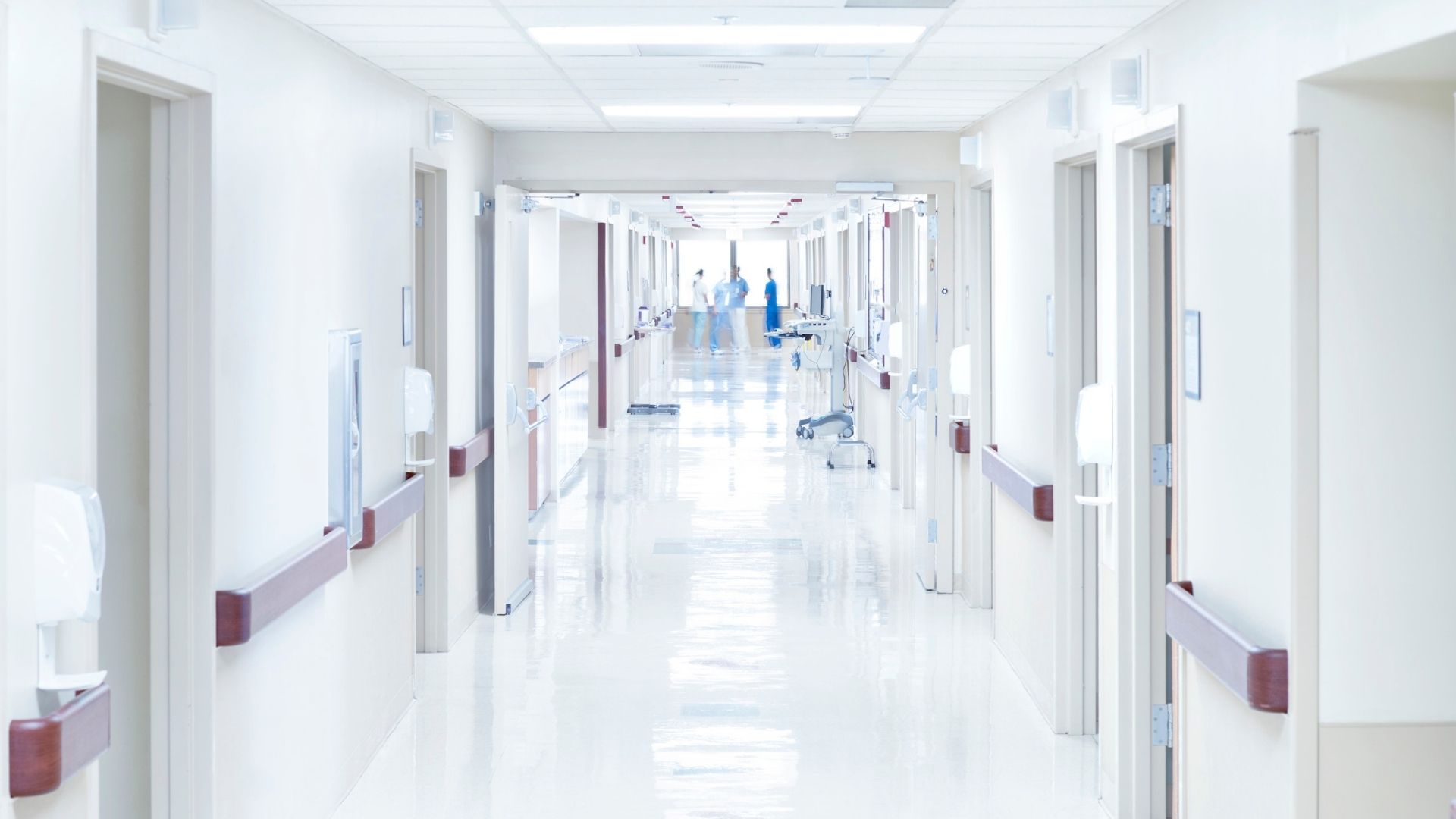Heller Krankenhausflur mit Patientenzimmern und medizinischem Personal