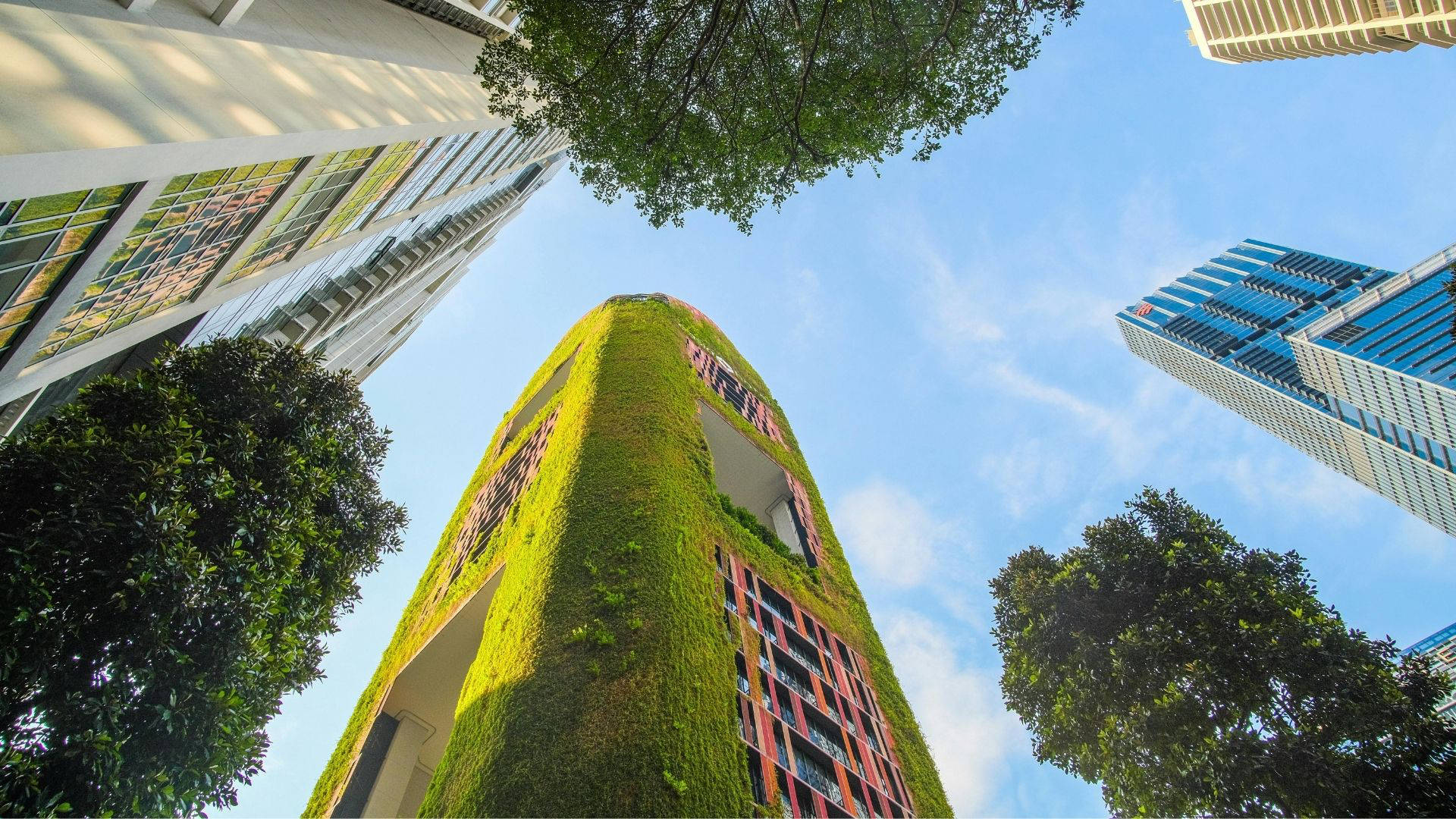 Begrüntes Hochhaus zwischen modernen Stadtgebäuden